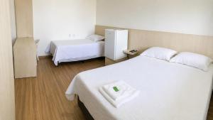 a bedroom with two beds and a refrigerator at Hotel Vanguarda Tapera in Tapera +10 photos