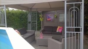 eine Veranda mit einer Couch und Stühlen unter einem Baldachin in der Unterkunft B&B Hoeven Het Gehucht in Overpelt