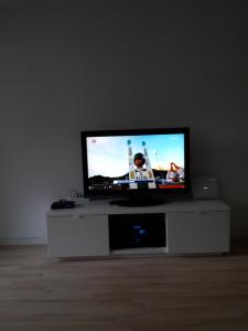 telewizor z płaskim ekranem siedzący na białym centrum rozrywki w obiekcie Ferienwohnung Sesvenna Davos w Davos