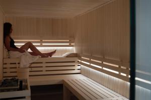 a woman is sitting in a sauna at Résidence & Spa Le Prince Régent in Paris