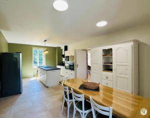 a kitchen with a wooden table and white cabinets at La Ferme de Sainte Isabelle in Montlay-en-Auxois +19 photos