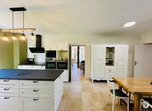 a kitchen with white cabinets and a wooden table at La Ferme de Sainte Isabelle in Montlay-en-Auxois