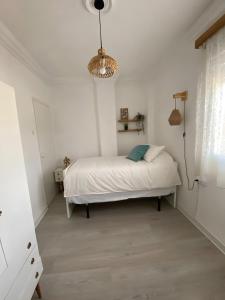 a white bedroom with a bed and a chandelier at Casa Perico Reyes in Cartagena