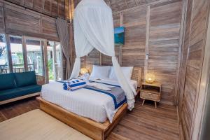 a bedroom with a bed with a mosquito net at The Old Island Huts in Nusa Lembongan