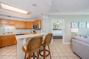 a kitchen with two bar chairs and a living room at Phoenix on the Bay 1405 in Orange Beach
