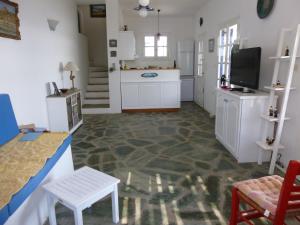a kitchen with white cabinets and a table and a tv at Villa Argos in Agios Georgios +27 photos