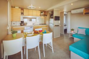 a kitchen and dining room with a table and chairs at Camping Bi-Village - Roan in Valbandon