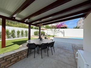 a patio with a table and chairs under a pergola at Apartment Ana Pool Residence in Preko