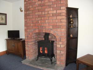 a brick fireplace with a stove in a room at Bryn Cottage in Llandderfel