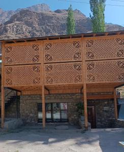 a building with a wooden roof with mountains in the background at Sho Hostel in Khorugh
