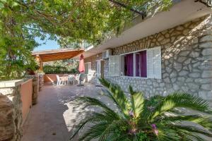 a villa with a patio and a house at Apartments Pepi in Mali Lošinj
