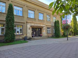 a building with the front entrance to a park with plants at Pasta Kvartāls Inn in Ogre +17 photos