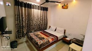 a small bedroom with a bed and a curtain at Hotel Kalyan in Rajkot
