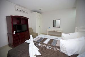 - une chambre avec un lit, une télévision et une commode dans l'établissement Hotel Principe, à Chetumal