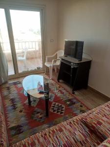 a living room with a tv and a coffee table at شاليه بقرية تاهيتي الساحل الشمالي in Al Ḩammām