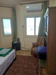 a bedroom with a bed and a couch and two windows at شاليه بقرية تاهيتي الساحل الشمالي in Al Ḩammām +8 photos