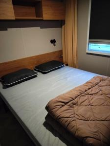 a large bed with two black pillows on it at Bienvenue chez Diamina et Patrick in La Tremblade