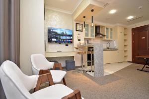 a living room with white chairs and a tv at Nord Gate Avenue Hotel in Yerevan