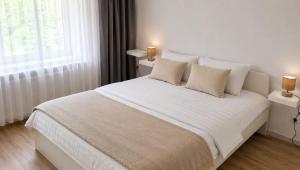 a bedroom with a large white bed with two lamps at Hanga Apartman in Băile Tuşnad