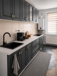 a kitchen with black cabinets and a sink at Hanga Apartman in Băile Tuşnad