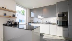 a kitchen with white cabinets and black appliances at Swiss Suites Oberglatt in Oberglatt