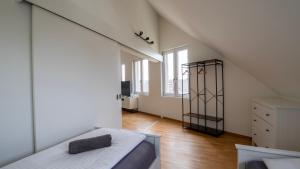 a white room with a bed and a dresser and windows at Swiss Suites Oberglatt in Oberglatt