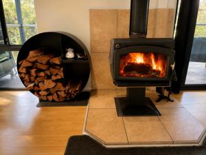 a wood stove in a room with a pile of logs at Kalamata - Adults Only Country Escape in Boyup Brook
