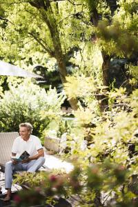 a man sitting on a bench in a garden at Romantik Hotel & Restaurant Stafler in Vipiteno