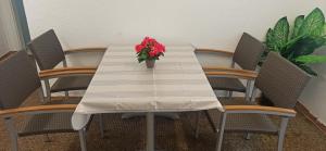 a white table with a vase of red flowers on it at Siggis und Anyas Ferienwohnung mit Sauna und XXXL-Dusche in Sasbachwalden +5 photos