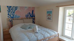 a bedroom with a white bed with blue pillows at Gîtes Le Bois Berranger in Saint-Urbain +39 photos