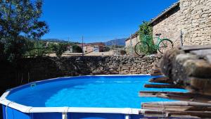 a large blue swimming pool next to a stone wall at Can Manuel in Gabet +34 photos