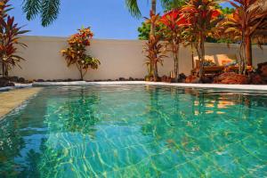 a swimming pool in a resort with palm trees at Hakuna Matata Bali Villas in Uluwatu