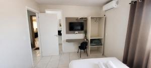 a small white room with a bed and a television at Hotel Goedert in Major Vieira