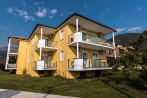 a yellow apartment building with balconies on a lawn at Studios Afrodite in Chrysi Ammoudia