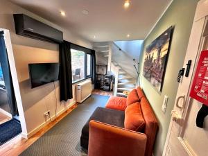 a living room with a couch and a tv at Barefoot Cottage in Noordwijk