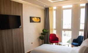a hotel room with a bed and two chairs and a television at Marchica Hotel in Nador