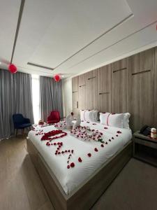a large bed with red rose petals on it at Marchica Hotel in Nador