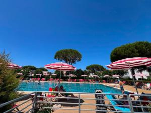 a swimming pool with red and white umbrellas and chairs at Casa vacanze Heidi con piscina in Marina di Bibbona