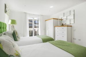 a white bedroom with two beds and a dresser at 8 Salt in St Ives