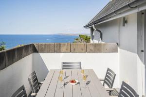 a wooden table and chairs on a balcony with the ocean at 8 Salt in St Ives