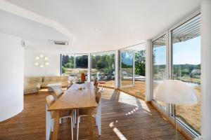 a dining room with a table and chairs and windows at Gite Design La Station in Angoisse