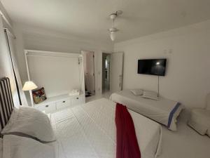 a bedroom with two beds and a flat screen tv at White House Canto in Búzios