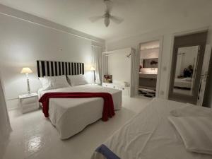 a white bedroom with two beds and two mirrors at White House Canto in Búzios