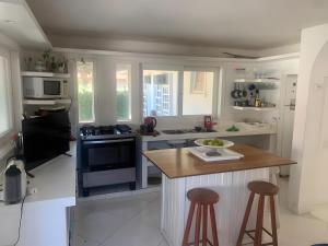a kitchen with white cabinets and a island with bar stools at White House Canto in Búzios