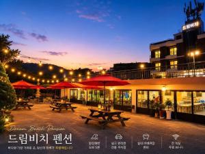 a patio with picnic tables and red umbrellas at night at Donhae Dream Beach in Donghae