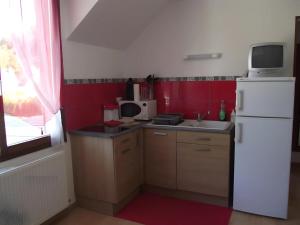a small kitchen with a white refrigerator and red walls at Chambre d'hôtes les Rosiers in La Flèche
