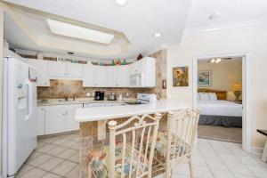 a kitchen with white cabinets and a room with a bed at Phoenix on the Bay 1415 in Orange Beach