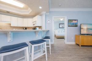 a kitchen with white cabinets and stools in a room at Phoenix on the Bay 1409 condo in Orange Beach