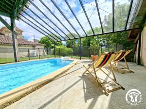 a pair of chairs sitting next to a swimming pool at Brasserie du Goutté in Roquefort
