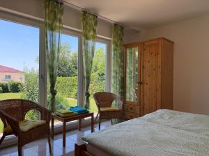 a bedroom with a bed and chairs and a large window at Casa Constantinus in Unteruhldingen